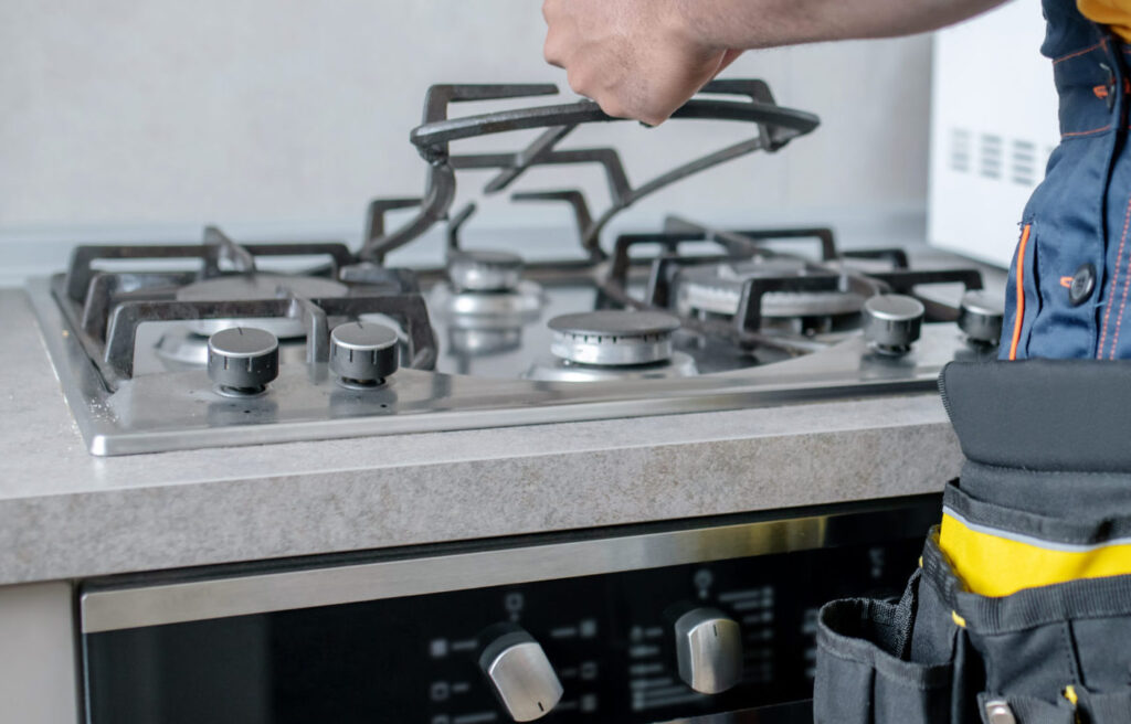 male service man in yellow tshirt repairing the gas stove