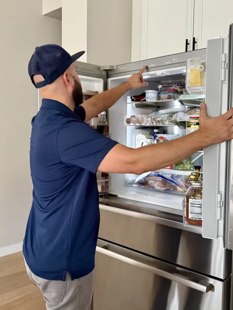 Appliance repair technician inspecting a Bosch French door refrigerator